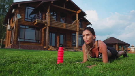 beautiful-brunette-on-the-background-of-a-large-mansion-engaged-in-fitness-and-performs-plank-exercise-for-the-press
