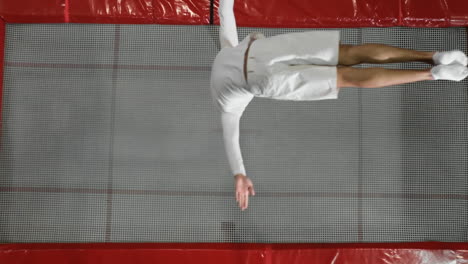 The-view-from-the-top-gymnast-acrobat-dressed-in-white-performs-a-somersault-on-the-trampoline