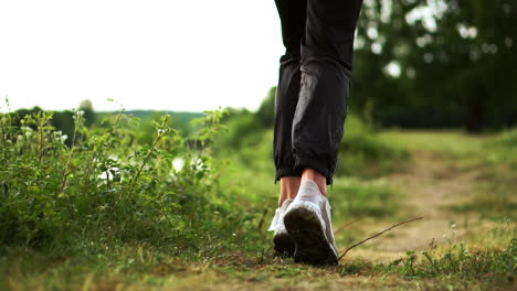 Close-up-of-feet-running-in-sneakers-along-the-river-on-the-grass