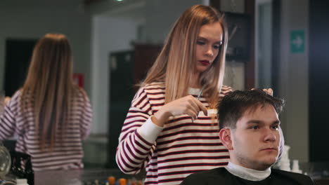 Female-hairdresser-cutting-hair-of-smiling-man-client-at-beauty-parlour