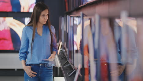 Smart-modern-female-customer-choosing-large-TV-sets-at-electronics-store.-New-screen-generations.