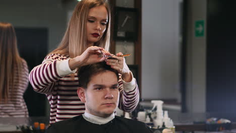 Female-hairdresser-cutting-hair-of-smiling-man-client-at-beauty-parlour