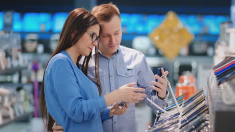 Happy-couple-buying-new-smart-phone-in-tech-store.-Deciding-which-model-to-purchase.