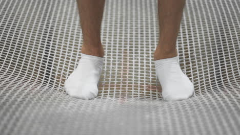 Close-up-of-feet-in-white-socks-are-on-the-trampoline-grid-and-swinging-to-jump-in-slow-motion.-The-beginning-of-speech.