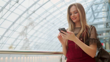 Girl-use-mobile-phone,-blur-image-of-inside-the-mall-as-background.