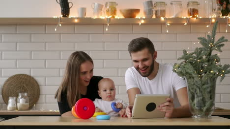 family-of-mother,-father-and-baby-sitting-at-home-with-a-tablet-PC