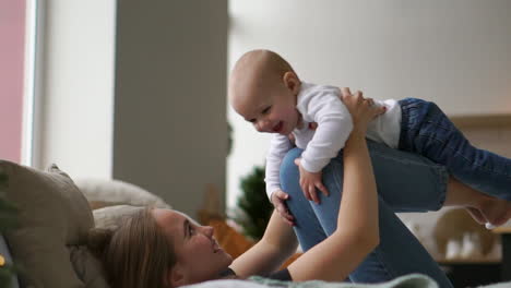 Concepto-De-Familia,-Maternidad-Y-Personas:-Madre-Feliz-Besando-Al-Pequeño-Bebé-Durante-Las-Vacaciones-Luces-De-Fondo