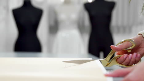 Schönes-Modedesigner-Mädchen,-Das-Auf-Papier-Mit-Goldenen-Scherenmustern-Für-Stoff-Auf-Schaufensterpuppen-Hintergrund-In-Hochzeitskleidern-Ausgeschnitten-Wurde.-Hersteller-Von-Brautkleidern.