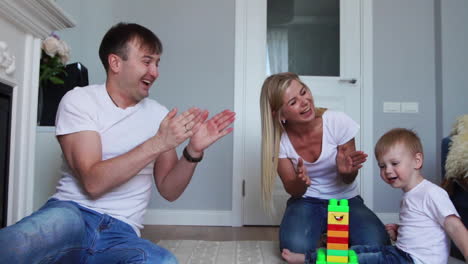 Dad-and-Mom-clap-their-hands-and-rejoice-at-the-success-of-the-little-son,-whipping-him-for-a-wave-of-task-from-Lego.