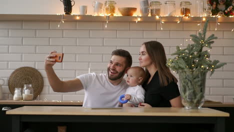 Smiling-parents-with-baby-taking-selfie-family-photo-on-bed-at-home