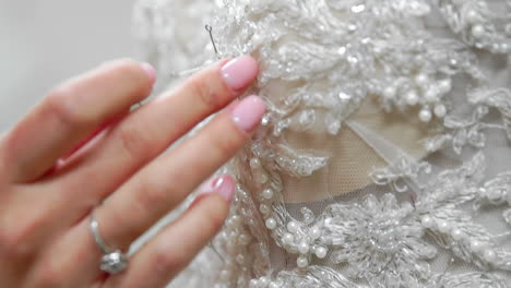 Close-up-fashion-designer-for-brides-in-his-Studio-pins-needles-lace-wedding-dress.-Seamstress-creates-an-exclusive-wedding-dress.-Secure-with-pins-and-needles-outline.-Small-private-business