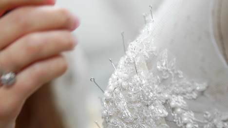 Close-up-fashion-designer-for-brides-in-his-Studio-pins-needles-lace-wedding-dress.-Seamstress-creates-an-exclusive-wedding-dress.-Secure-with-pins-and-needles-outline.-Small-private-business