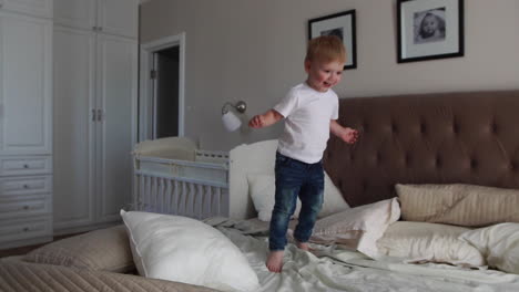 A-boy-in-a-white-T-shirt-jumps-on-the-bed-and-laughs-at-the-sight-of-soap-bubbles-in-the-parents'-bedroom-in-slow-motion