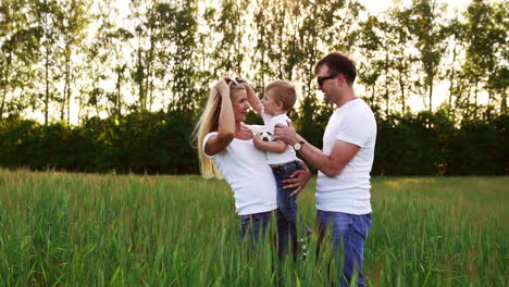Young-parents-go-to-the-field-with-spikelets-of-wheat-in-white-T-shirts-and-jeans