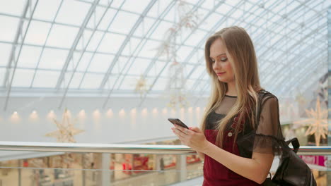 Girl-use-mobile-phone,-blur-image-of-inside-the-mall-as-background.