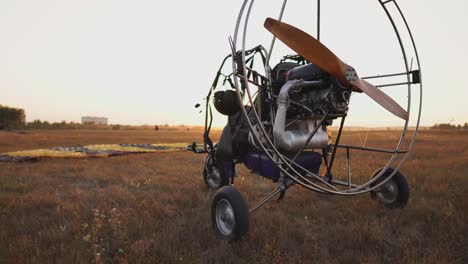 Motor-paraglider-stands-at-the-airport-in-the-rays-of-sunset-sunlight.-The-camera-moves-along-the-orbit