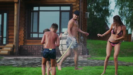 Family-in-the-backyard-of-a-country-house-in-the-summer-relax-playing-with-water-and-hosing