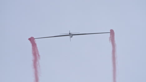 Amazing-scene-of-aerobatic-Glider-doing-tricks-with-red-smoke,-tracking-shot