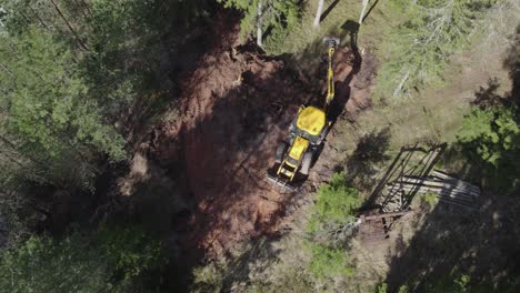 JCB-tractor-working-in-forest,-taking-out-tree-roots-drone-shot-from-above