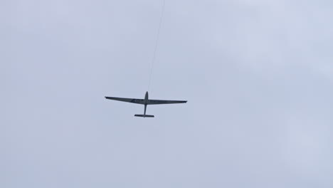 Glider-attached-to-another-airplane-to-take-off,-tracking-shot,-overcast-day