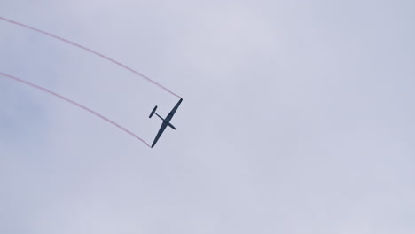 Wide-tracking-shot-view-of-Glider-aerobatic-flying-releasing-red-smoke-in-air
