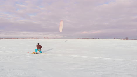 A-man-is-skiing-in-the-snow-in-a-field-at-sunset.-His-parachute-pulls.-Kite-surfing-in-the-snow..