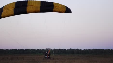 The-motor-paraglider-lowers-the-parachute-after-landing-and-stops-completely-in-the-field-after-sunset