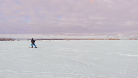 A-man-is-skiing-in-the-snow-in-a-field-at-sunset.-His-parachute-pulls.-Kite-surfing-in-the-snow..