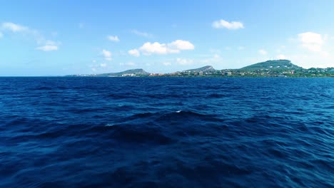 Tief-Fliegender-Luftwagen-Nähert-Sich-Der-Küste-Der-Karibischen-Insel-Curacao,-Ruhige,-Sanfte-Wellen-An-Einem-Tag-Mit-Blauem-Himmel