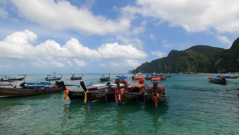 Traditional-longtail-boats-at-the-shore-of-the-Andaman-Sea-at-famous-Kho-Phi-Phi-Island,-Thailand,-Pullout-shot