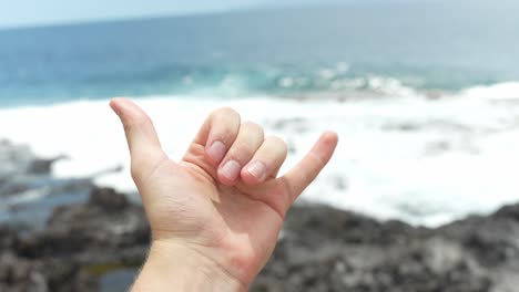 Happy-person-show-cool-hand-gesture-while-standing-near-rocky-coast-of-Tenerife