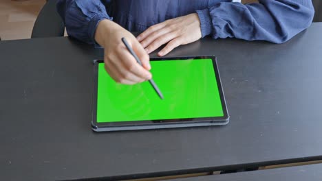 Young-female-hands-sketching-on-tablet-with-digital-pencil,-at-wooden-desk