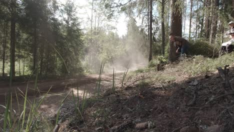 WRC-rally-in-Estonia,-fast-rally-car-fly-s-bye-on-high-speed-on-gravel-road-surrounded-by-forest,-dust-cloud-is-seen-in-sunlight