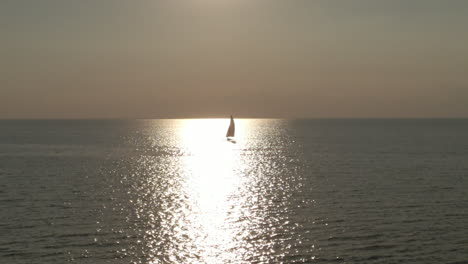A-panning-aerial-view-of-a-sailboat-on-a-lake-at-sunset