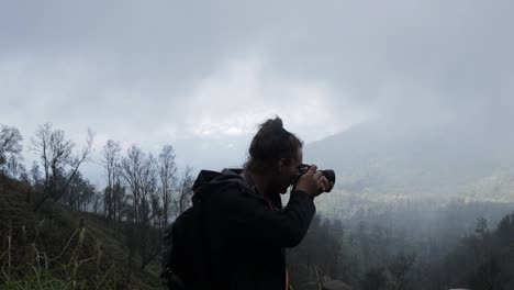 Caucasian-backpacker-man-taking-photo-in-foggy-smoke-forest-mountain