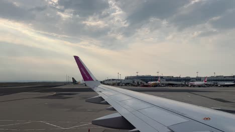 Wizz-Air-plane-wing-in-the-international-airport-of-Vienna,-Flughafen-Wien-Schwechat-during-the-day-4K