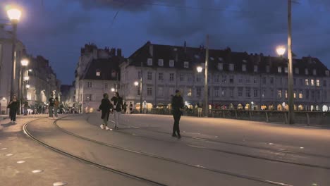 City-Besancon-in-Franche-Comté-night-life-with-people-walking-over-pedestrian-bridge-with-tram-tracks-and-streetlights