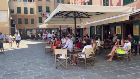 Tourists-sit-by-the-cafe,-having-coffee-and-people-watching-during-the-summertime-holidays-in-Camogli,-Italy