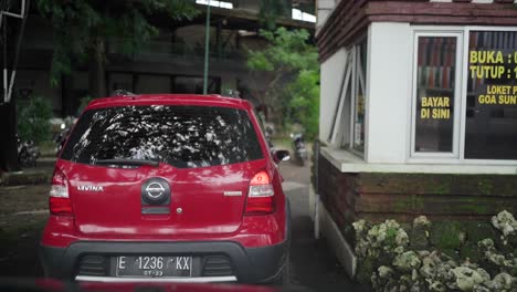 Driver-in-car-paying-with-money-at-the-operator's-POS-or-ticket-counter-to-enter-the-Cirebon-Sunyaragi-Cave-cultural-reserve