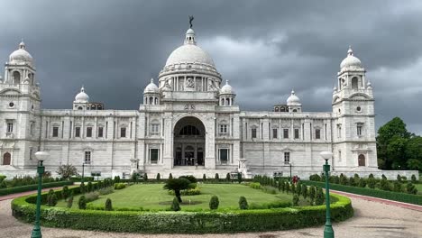 Low-angle-shot-of-beautiful-white-marble-called-Victoria-Memorial-in-Kolkata,-West-Bengal,-India-with-dark-cloud-movement-in-the-background-on-a-cloudy-day