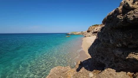 Shiny-morning-on-paradise-beach-between-the-cliffs-washed-by-blue-turquoise-sea-on-a-summer-day-vacation-in-Albanian-coastline