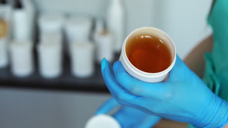 Close---up-of-hands-in-rubber-gloves-open-a-jar-of-sugar-for-hair-removal-by-sugaring