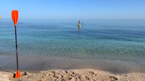 Mädchen-Beim-Pfützensurfen-Im-Meer-In-Nerja-Malaga,-Stand-Up-Pfützenboarden-An-Einem-Sonnigen-Tag-In-Spanien,-Lustige-Urlaubsaktivität,-Abenteuerlicher-Wassersport,-4K-Aufnahme