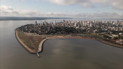 Aerial-view-of-the-coastal-city-of-Posadas-Misiones-Argentina,-drone-shot-of-densely-populated-coastal-city-cloudy-sky