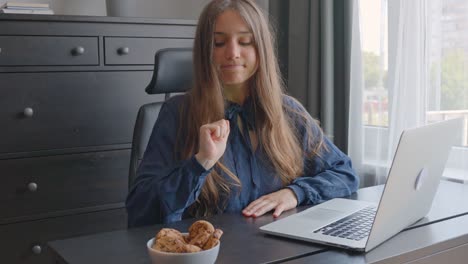 Portrait-of-woman-on-diet-in-office-tempted-to-eat-cookies-on-desk-while-working