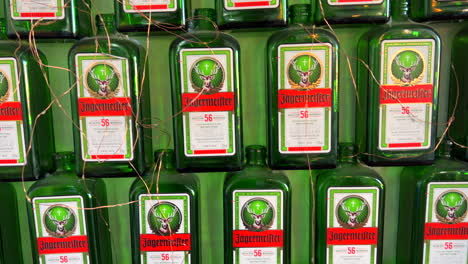 Muchas-Botellas-Verdes-De-Alcohol-Digestivo-Alemán-Jägermeister-En-Una-Pared,-Bebida-Alcohólica,-Toma-De-4k