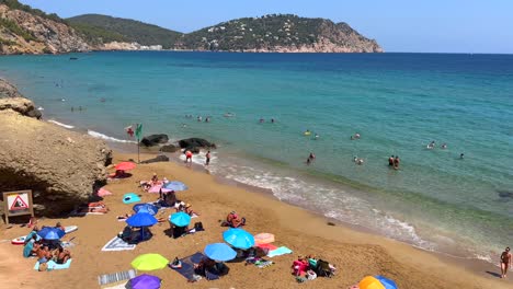 Summer-dream-vacation-destination-beach-in-north-of-Ibiza-Spain,-transparent-turquoise-water,-people-on-holiday,-4K-shot