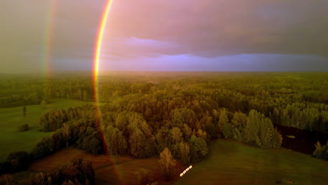Eine-Drohnenantenne-Senkt-Sich-über-Einen-Regenbogenbogen-Aus-Bewaldetem-Ackerland