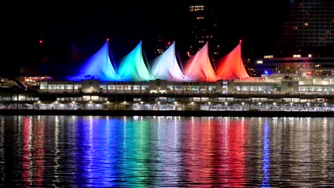 4k-CANADA-PLACE-Sails-of-Light-at-Night-Reflecting-on-water,-Downtown-Vancouver-British-Columbia,-seen-from-Stanley-Park-sea-wall