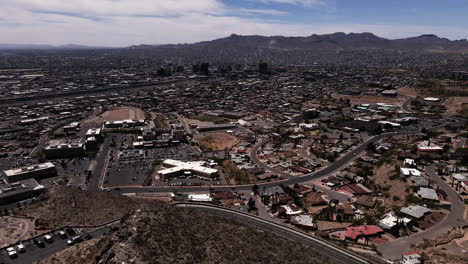 Aerial-reveal-of-El-Paso,-TX-skyline-with-mountains-in-the-distant